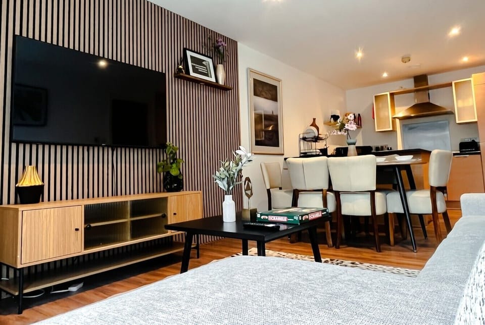 Living room from the sofa showing the TV wall, coffee table and dining area with kitchen beyond.