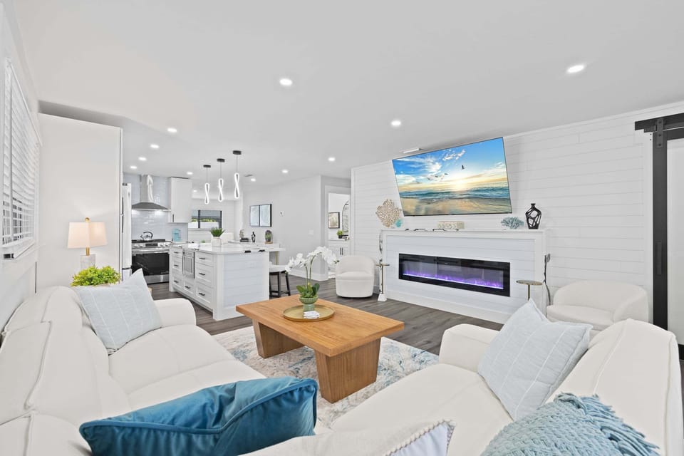 Open-concept living with fireplace, TV, and seamless flow into the kitchen—great for gathering.