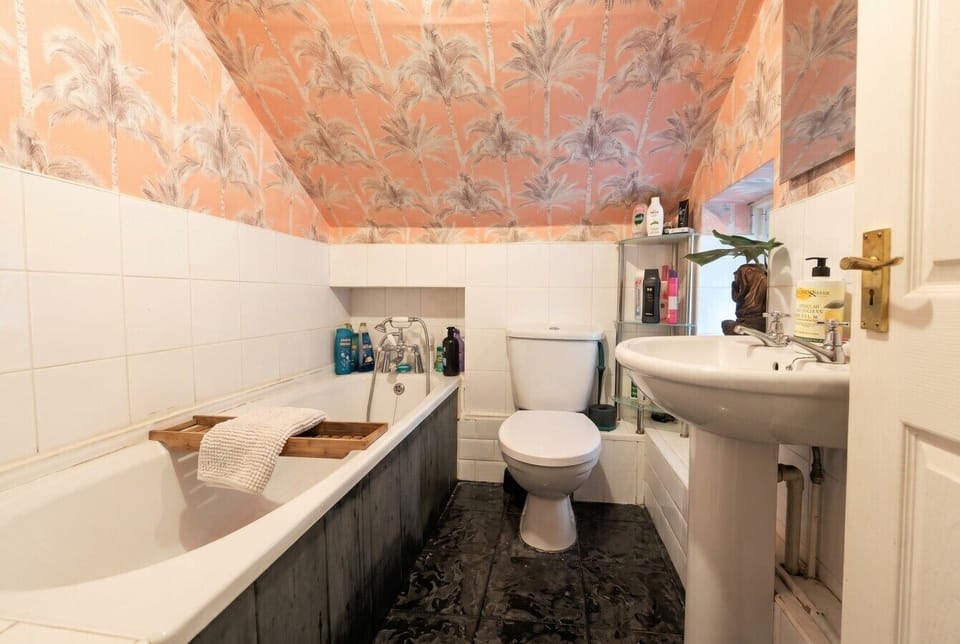 Full bathroom with a soaking tub and striking palm-print wallpaper ceiling.