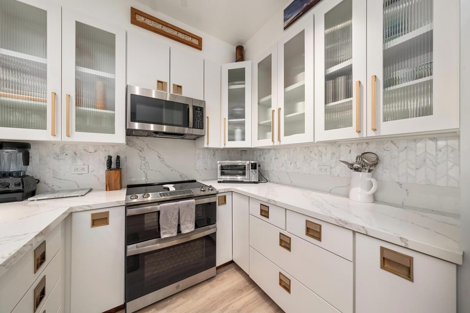 You'll love preparing meals in this elegant kitchen featuring marble countertops, glass-front cabinets, and modern appliances.