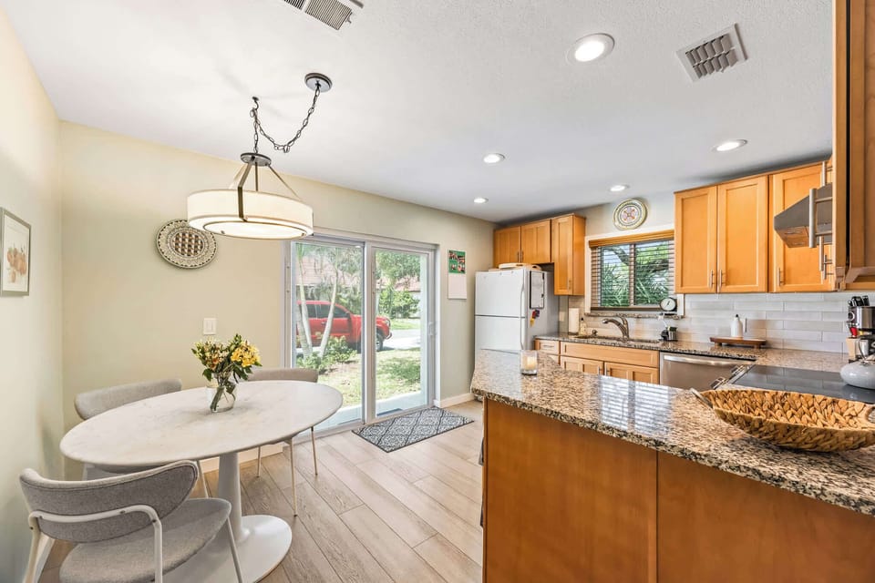 Bright kitchen and dining area with granite countertops and sliding glass doors to the outside.