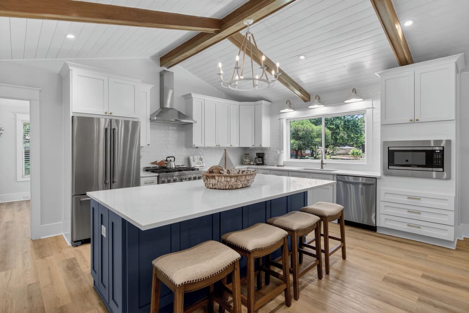 Picture yourself cooking in this stunning kitchen with vaulted ceilings, exposed beams, and a large island perfect for gathering. Modern appliances and abundant natural light make your stay effortless and inviting.
