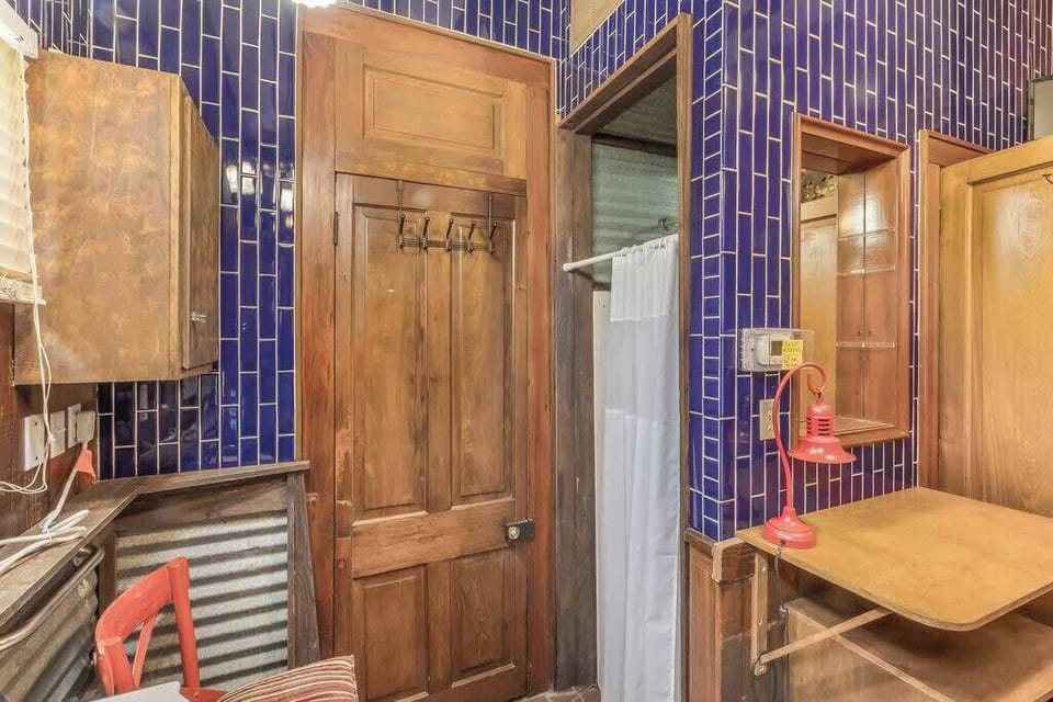 With a shower tucked behind the curtain, the area features bold tile accents and a clean, functional layout.