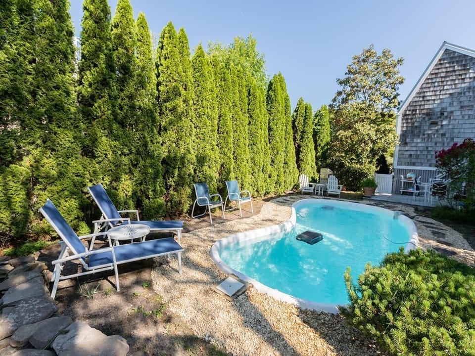 Private outdoor pool with lounge chairs and lush landscaping, perfect for relaxing in the sun.