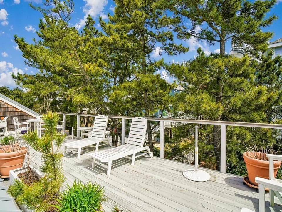 Spacious outdoor upper deck with comfortable lounge seating surrounded by mature pine trees.