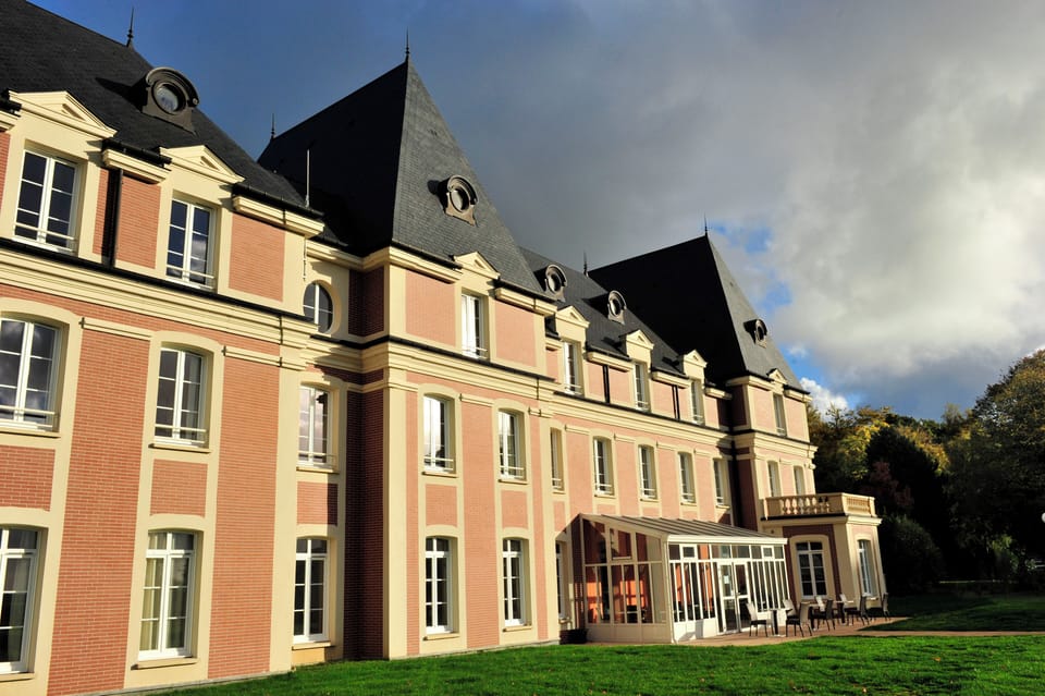 Pitched slate rooftops and dormer windows mark the château building, home to 28 apartments with elevator access