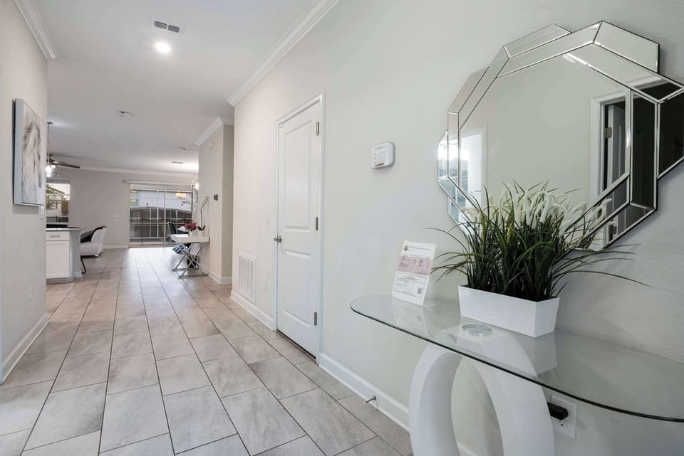 Entryway with modern glass console table and decorative mirror leading to the open living area