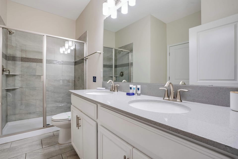 Modern bathroom featuring a dual sink vanity and glass-enclosed shower with tiled walls.