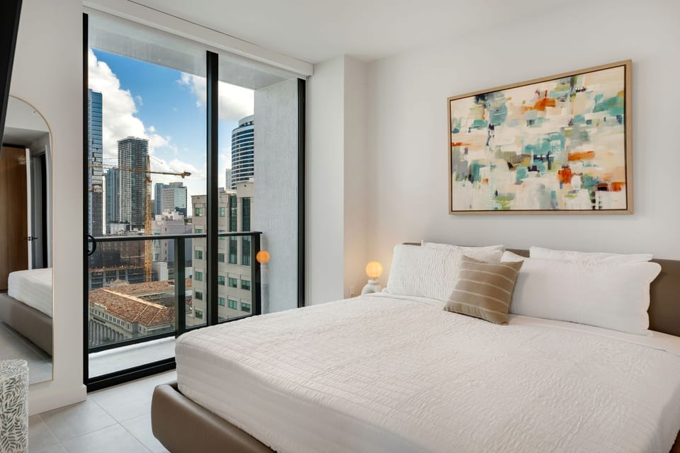 Comfortable bedroom with floor-to-ceiling windows and city views.