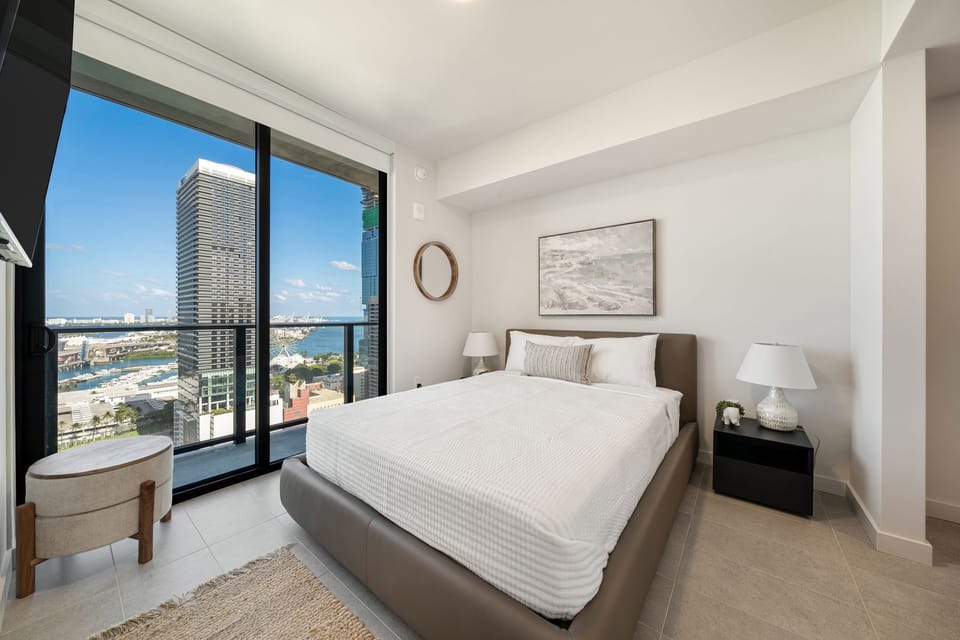 Bright bedroom with floor-to-ceiling windows and city views.