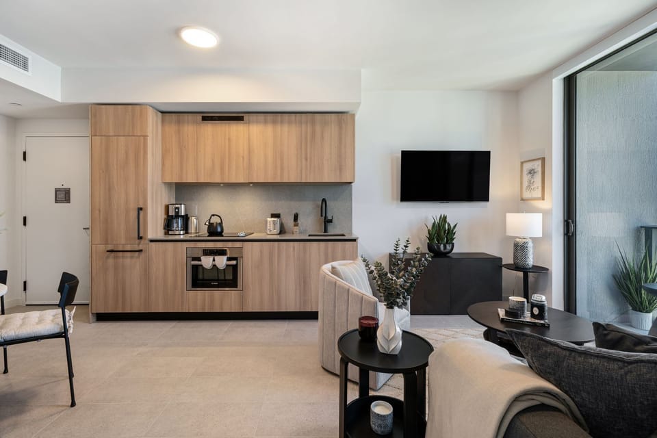 Modern kitchenette with warm wood finishes and an open living layout.