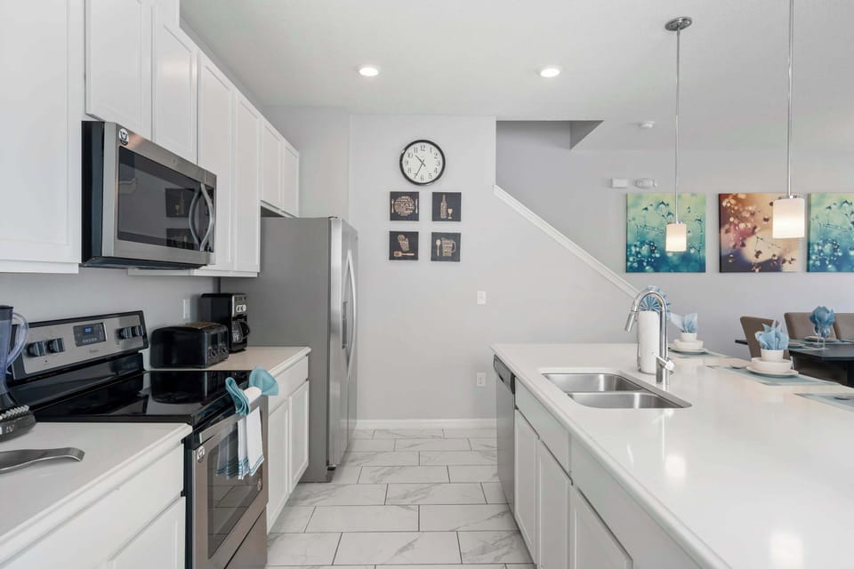 Fully equipped chef's kitchen-sleek white cabinets, ample counter space, and a double-sink island that opens to the dining area.