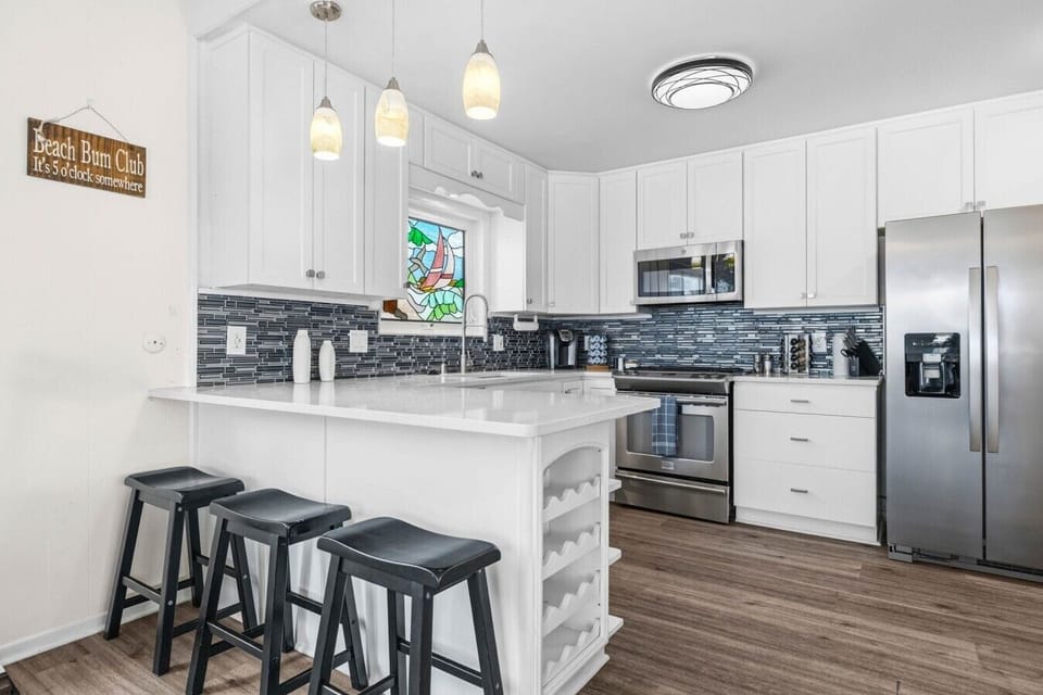 Modern, fully equipped kitchen with breakfast bar seating and stainless steel appliances.