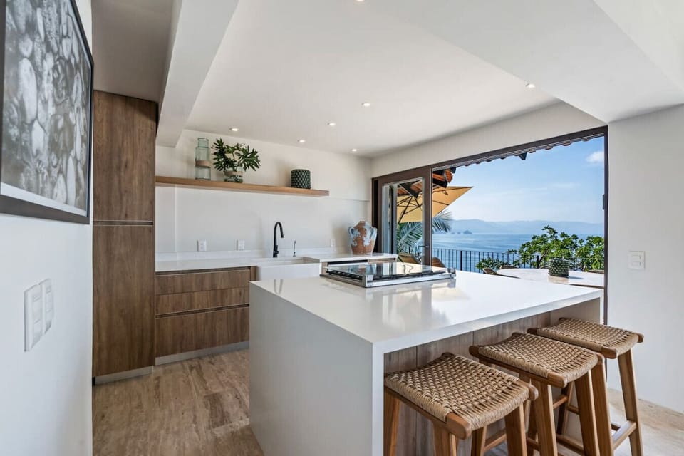Gather around this elegant breakfast bar in a Puerto Vallarta kitchen designed for style. This luxury rental near Playa Conchas Chinas offers seamless indoor-outdoor living and breathtaking ocean views for your family vacation.