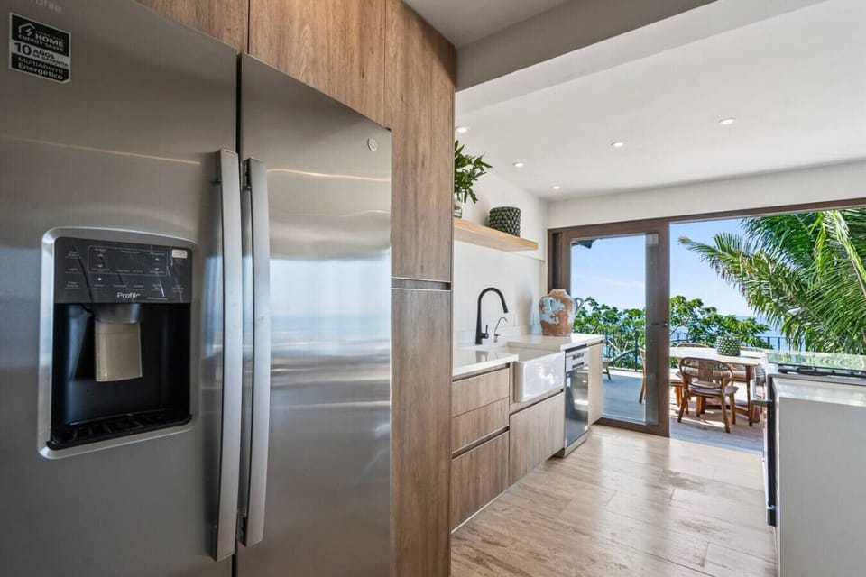 Chef-ready kitchen in this Puerto Vallarta luxury rental featuring sleek appliances and stunning ocean views. The open design connects to a balcony, perfect for entertaining during your next family vacation near Playa Conchas Chinas.