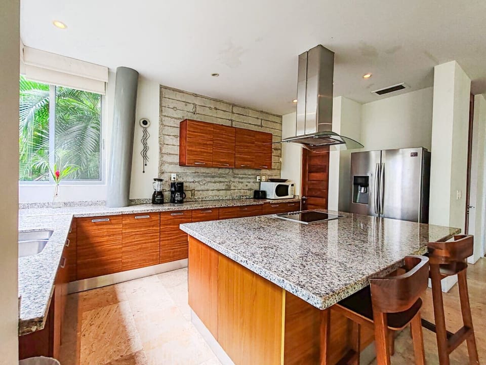 Fully equipped kitchen with granite countertops, breakfast bar, stainless fridge, cooktop, and plenty of prep space. Includes coffee maker and essentials for cooking at home—perfect for family meals after the beach in Puerto Vallarta.