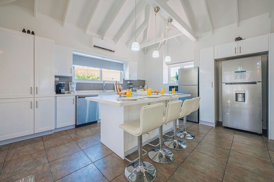 Bright kitchen with central island, bar seating, and high ceilings creating an open, airy gathering space