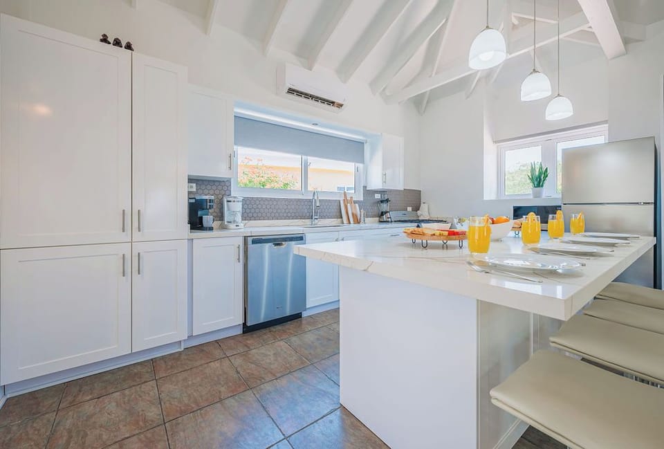 Kitchen workspace with wide counters, stainless appliances, and window light enhancing the fresh, modern design