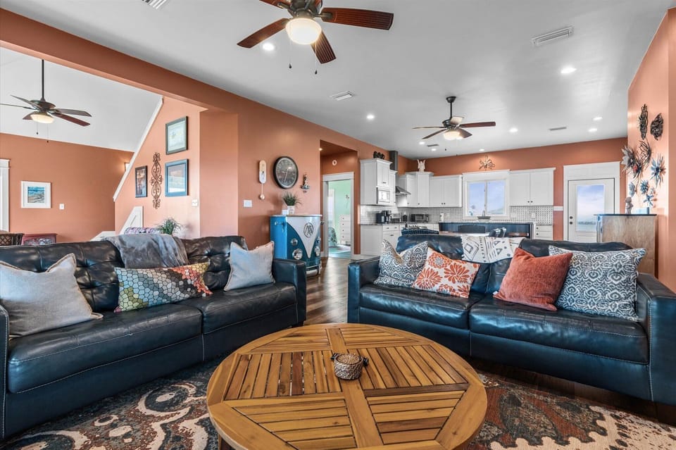 Sink into plush leather sofas surrounded by warm coral walls and coastal charm, where ceiling fans keep you cool as you relax.