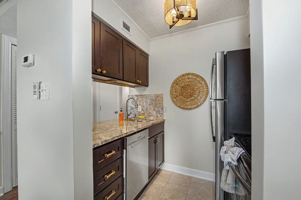 Your fully equipped kitchen features granite countertops, stainless steel appliances, and elegant dark wood cabinetry—perfect for preparing meals during your stay.