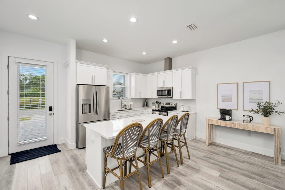 Step into your bright, open kitchen where clean white cabinetry and modern appliances make meal prep a breeze. Gather at the spacious island with seating for four to enjoy morning coffee.