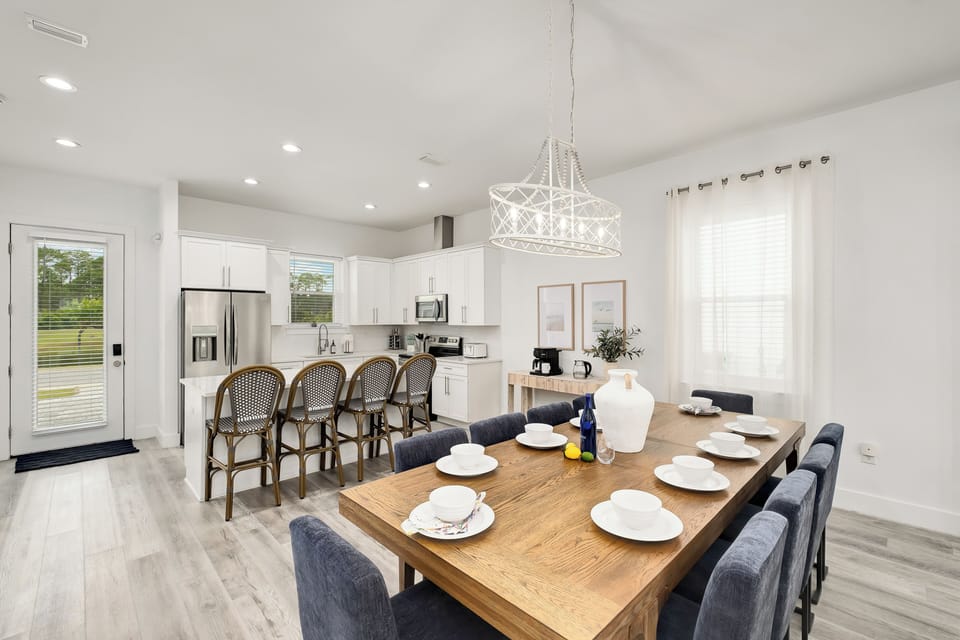 Gather around this bright, airy dining space where your group can enjoy meals together. The open kitchen, island seating, and large table create a welcoming heart of the home for your stay.