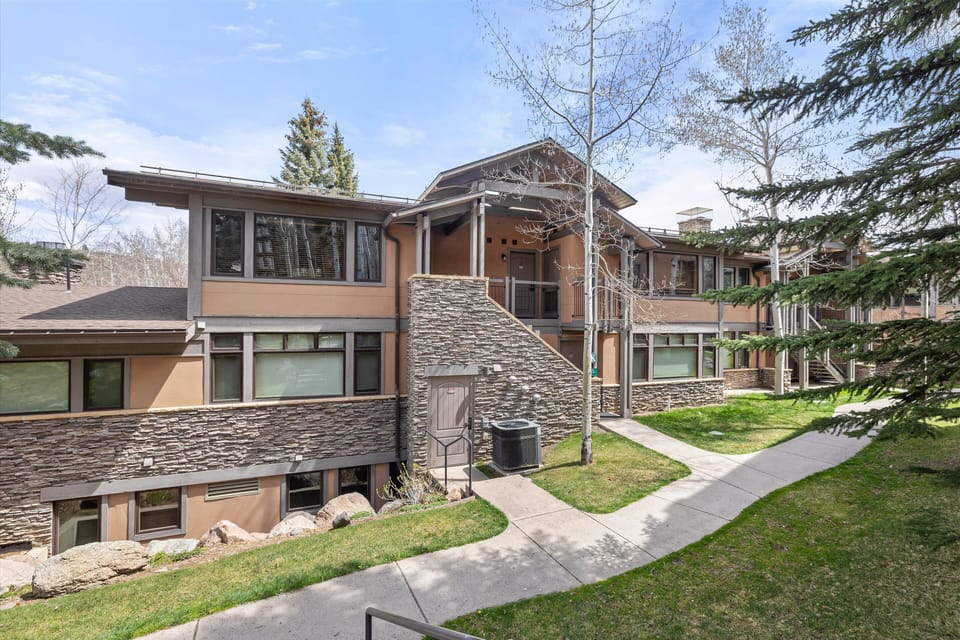 Modern mountain retreat featuring stone and stucco architecture nestled among mature evergreen trees.
