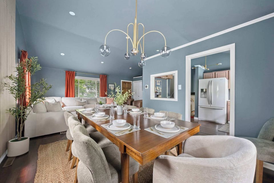 Elegant dining room w/ a statement chandelier, round table & comfortable upholstered chairs.
