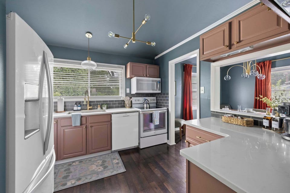 Open kitchen w/ dark cabinetry, a central island & warm wood floors.
