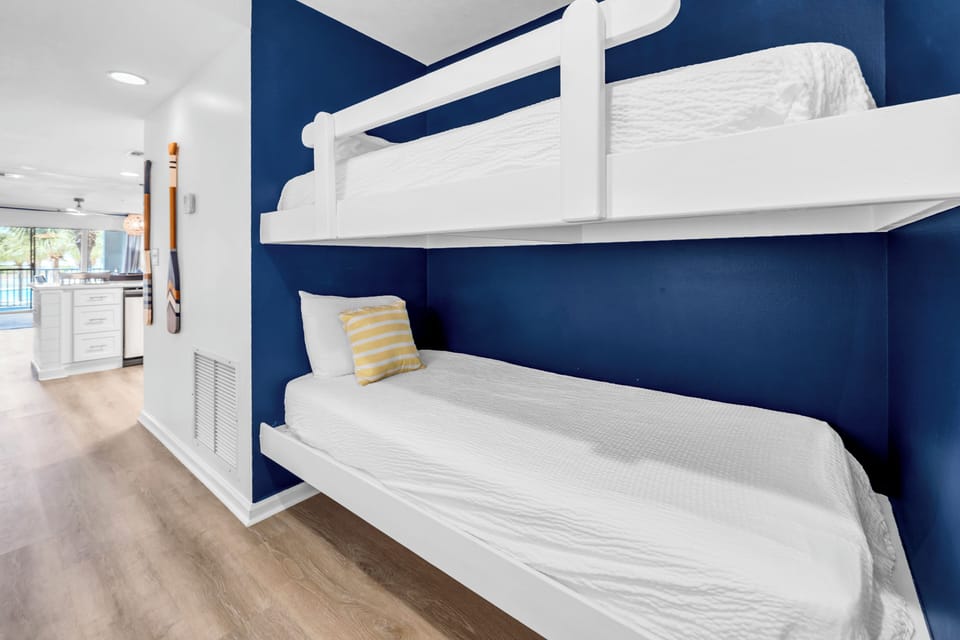 Settle into these crisp white bunk beds with their cheerful yellow accent pillow - perfect for a restful night's sleep.