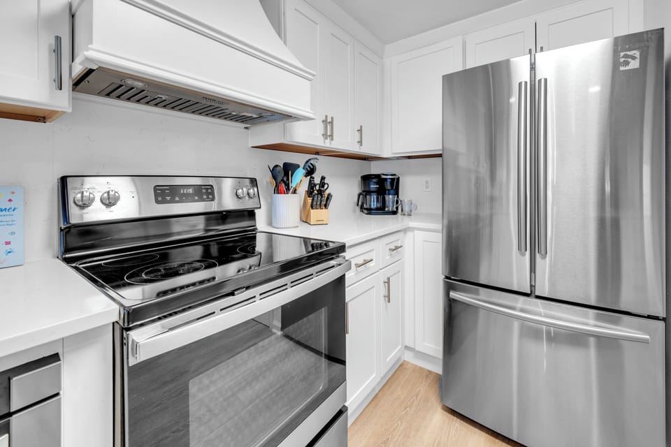 Your fully-equipped kitchen features stainless steel appliances and sleek white cabinetry, perfect for preparing meals during your stay.