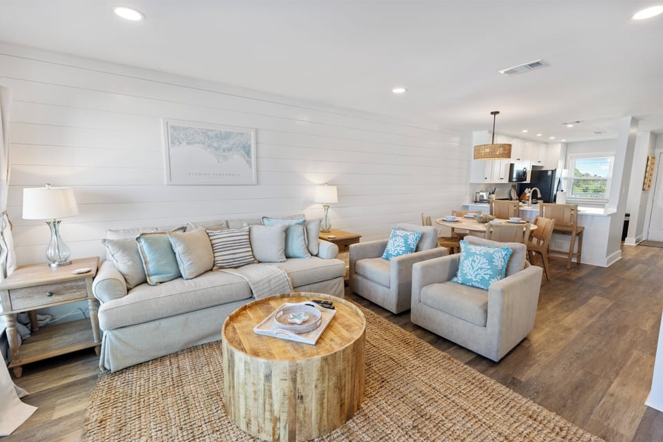 Your coastal-inspired living space flows seamlessly into the open kitchen, where soft blues and natural textures create the perfect backdrop for relaxing evenings.
