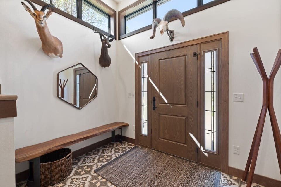 A welcoming entry featuring a stylish wooden door, bench seating, and curated décor accents that set a warm and inviting tone upon arrival.
