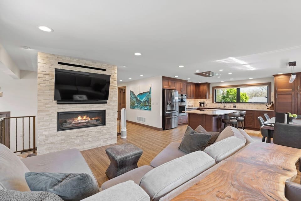 An inviting open-concept living area with a warm fireplace seamlessly flows into the modern kitchen.