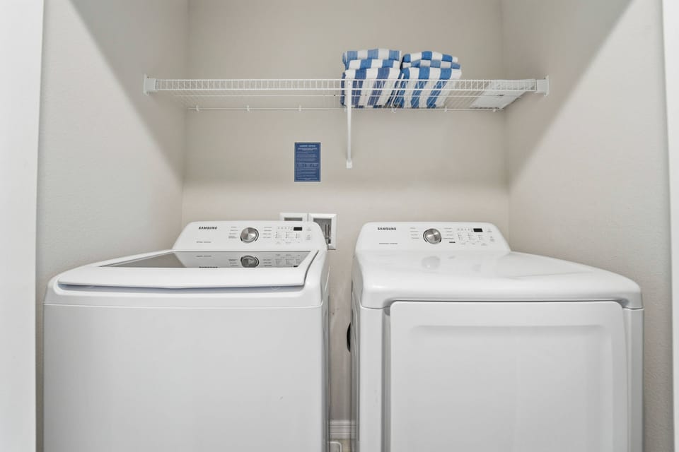 Keep clothes fresh during your stay with a convenient laundry area featuring a washer, dryer, storage shelf, and pool towels, offering extra comfort and practicality for your vacation.