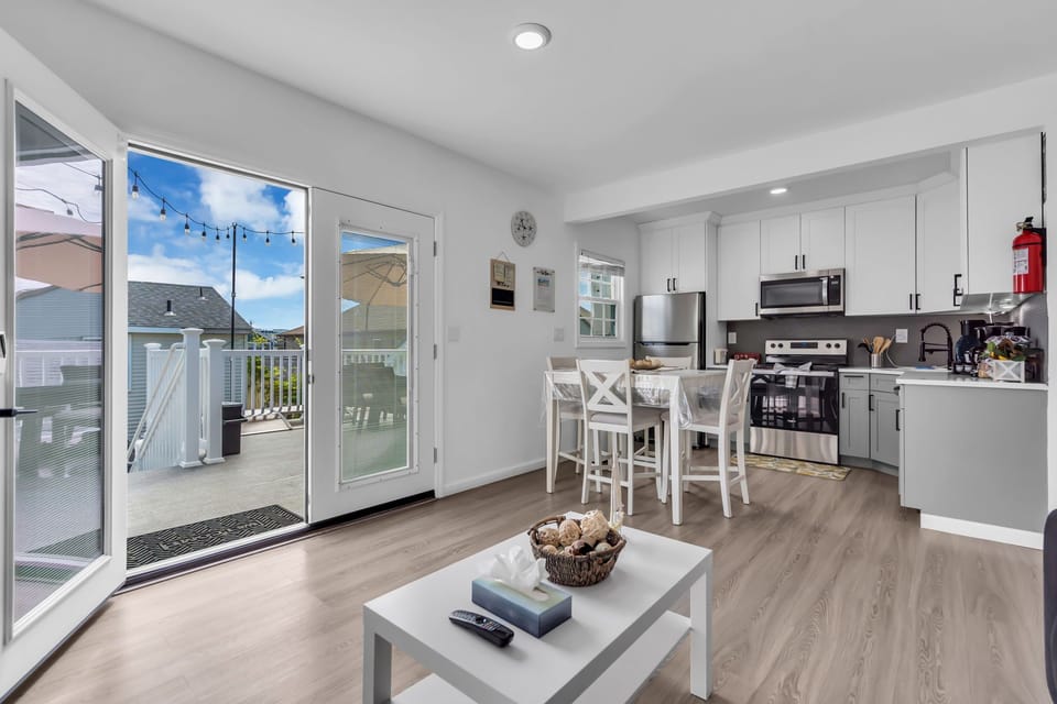 Sunny open-plan kitchen/living with deck access and string-lit patio.