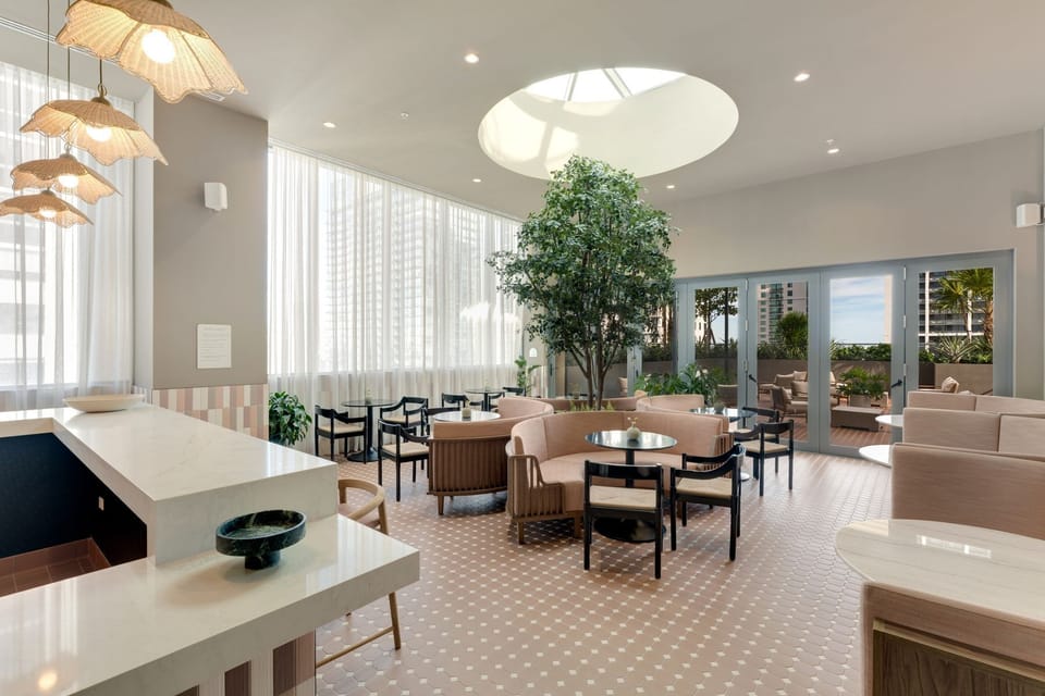 Bright social lounge with dining areas, natural light, and elegant design.