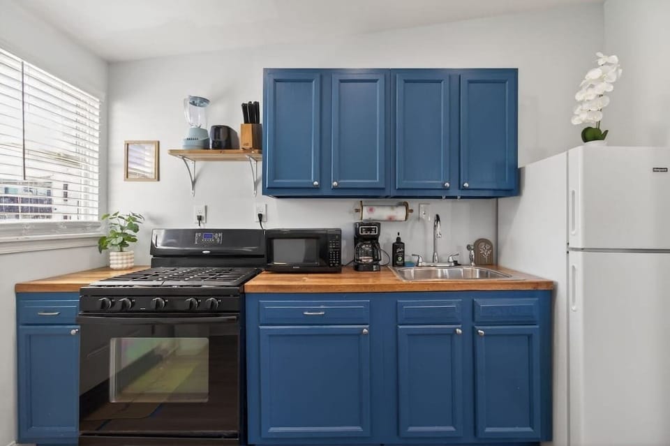 Fully equipped kitchen with blue cabinetry, a stove, microwave, coffee maker, and refrigerator—everything you need for convenient home cooking during your stay.