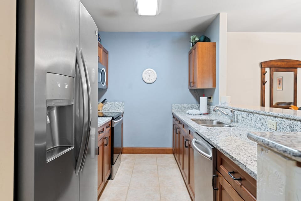 Your fully equipped galley kitchen features stainless steel appliances, elegant granite countertops, and warm wood cabinetry—perfect for preparing home-cooked meals during your stay.