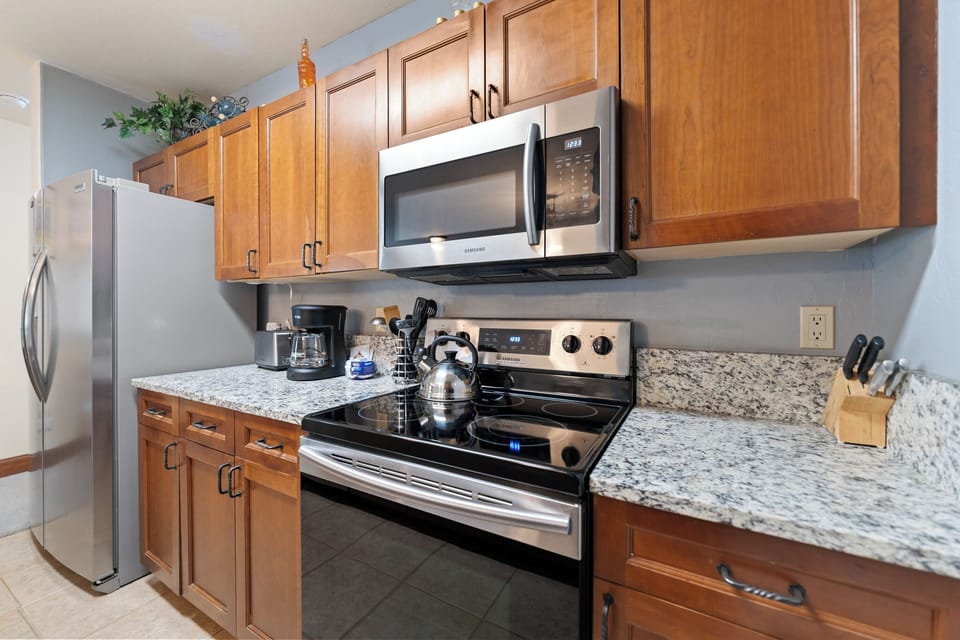 Your fully equipped galley kitchen features stainless steel appliances, elegant granite countertops, and warm wood cabinetry—perfect for preparing home-cooked meals during your stay.