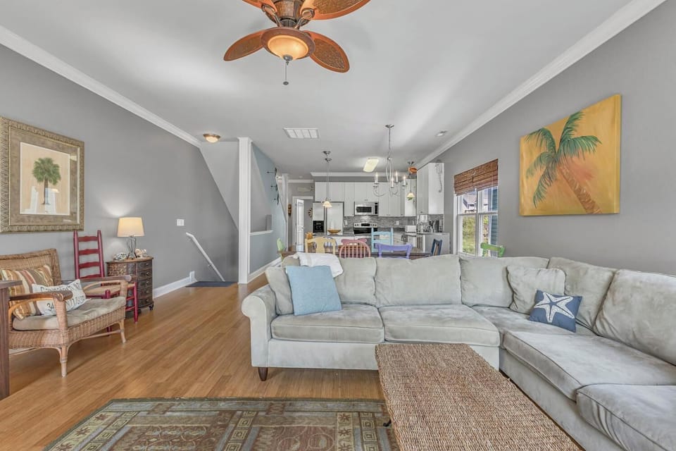 Settle into your coastal-inspired living room with plush sectional seating, tropical artwork, and an open flow to your fully equipped kitchen.