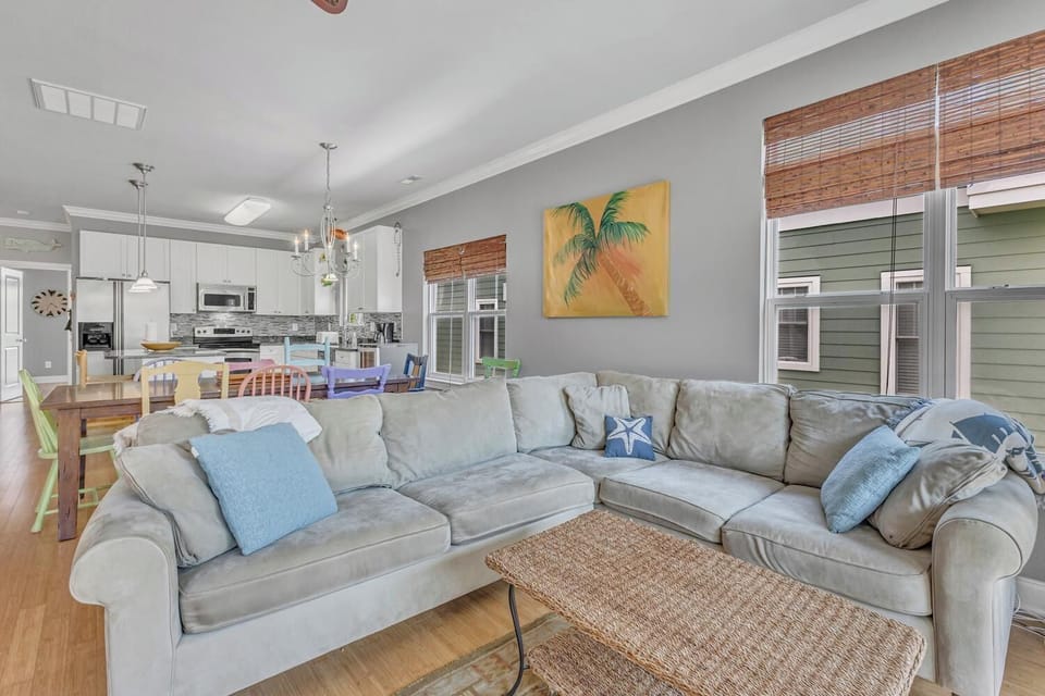 Relax on your spacious sectional sofa in this open-concept living space, where coastal decor and natural light create the perfect atmosphere.