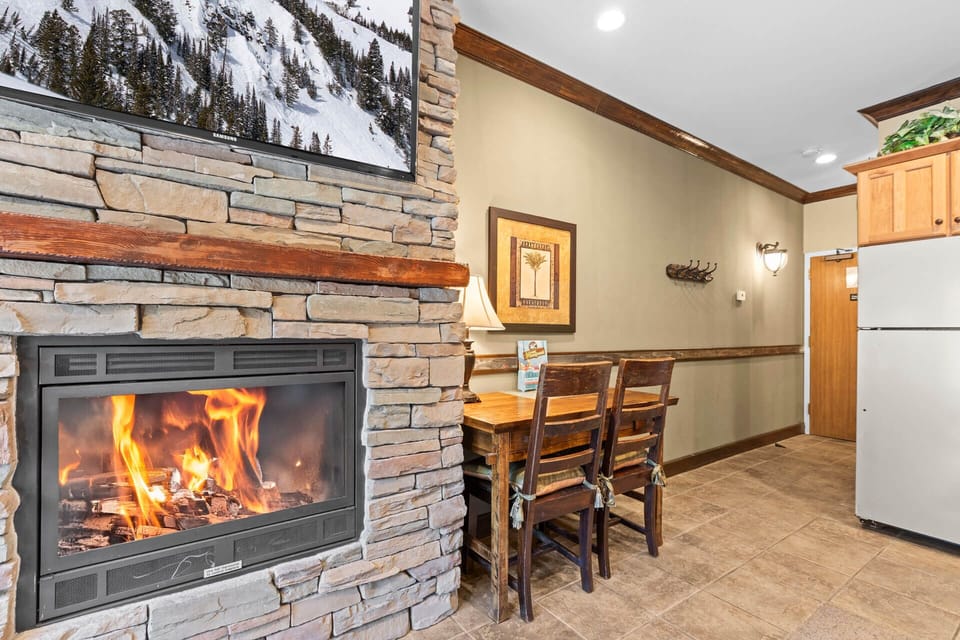 Warm up by the stone fireplace after a day on the slopes, then gather at the dining table—this cozy spot blends rustic charm with mountain comfort perfectly.