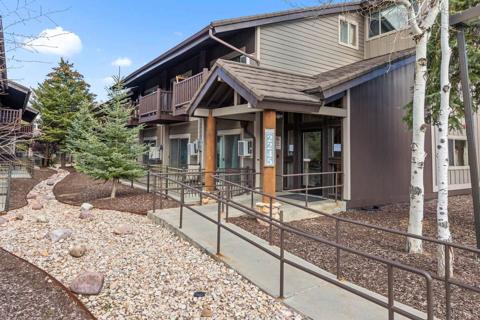 A welcoming mountain property with accessible entrance ramps, surrounded by evergreens and aspens, offering easy arrival and a peaceful alpine setting.