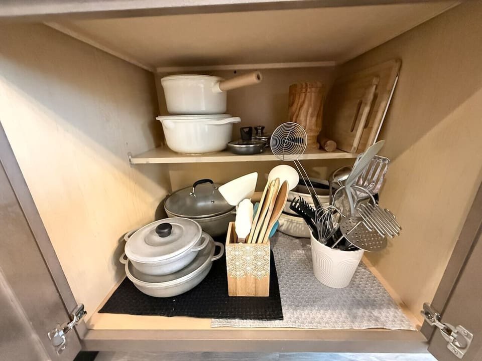 Kitchen cabinet with pots, pans, and essential cooking tools.