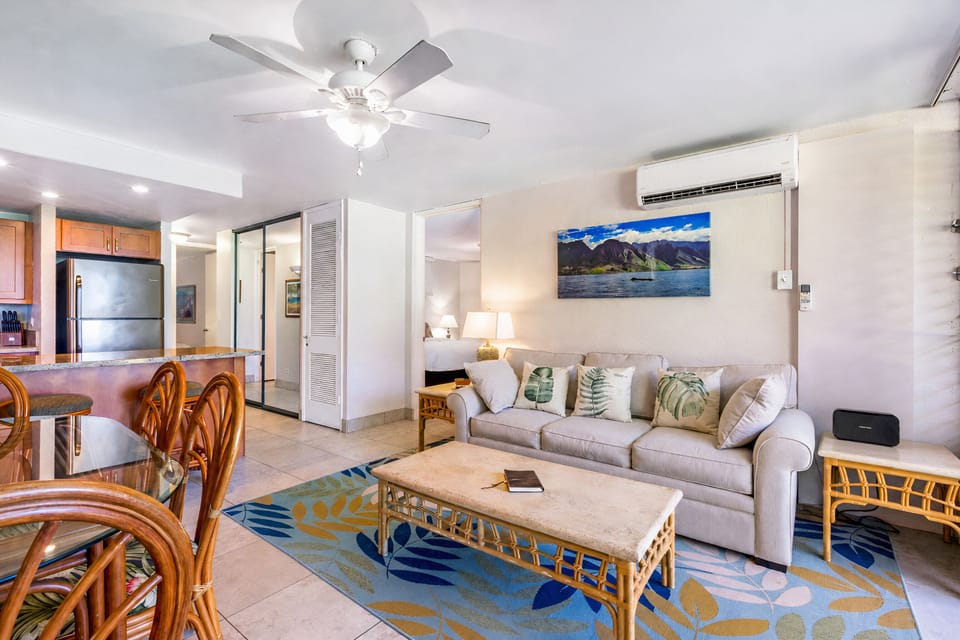 The open-concept living area is designed for comfort, featuring a large sofa, tropical-inspired decor, and a seamless flow into the dining space.