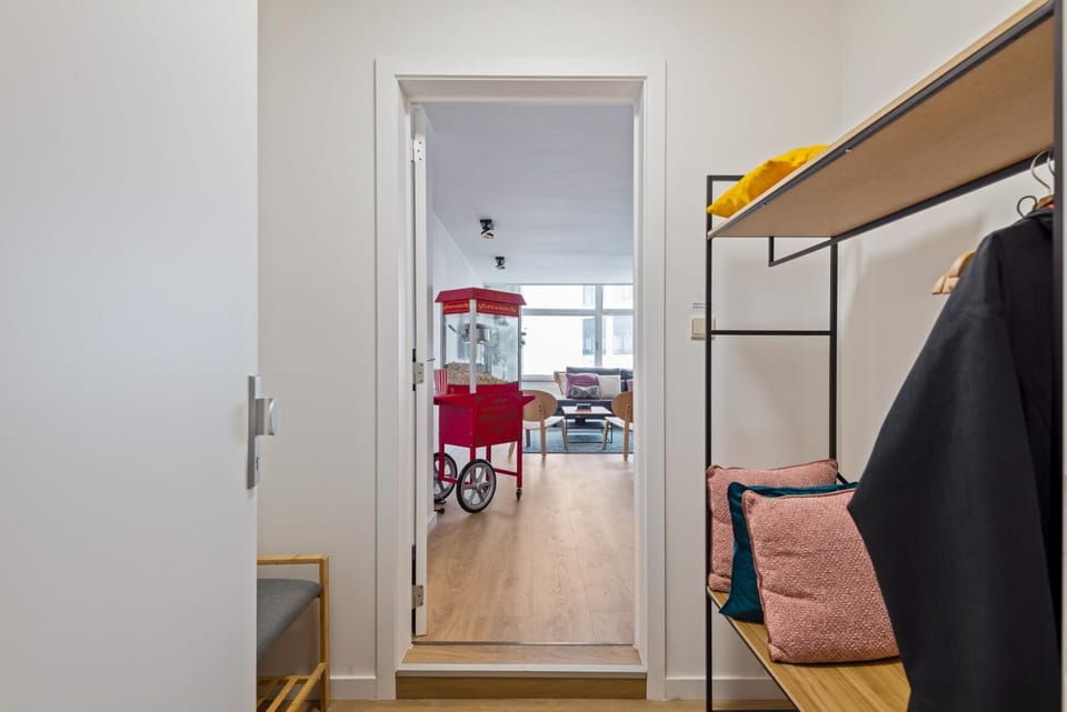 Entryway with coat rack, seating bench, and storage space for jackets and bags. The hallway leads directly into the bright living area, creating an easy and welcoming transition when entering the apartment.