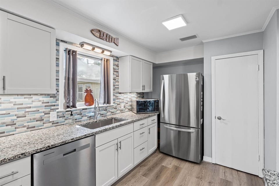 Step into your fully equipped kitchen with granite countertops, stainless steel appliances, and stylish backsplash—perfect for preparing meals during your stay.