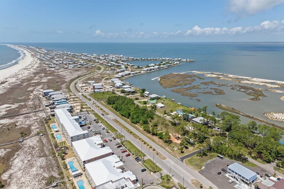 Aerial view of coastal community featuring white sand beaches, waterfront homes, and protected harbor areas along the Gulf Coast.