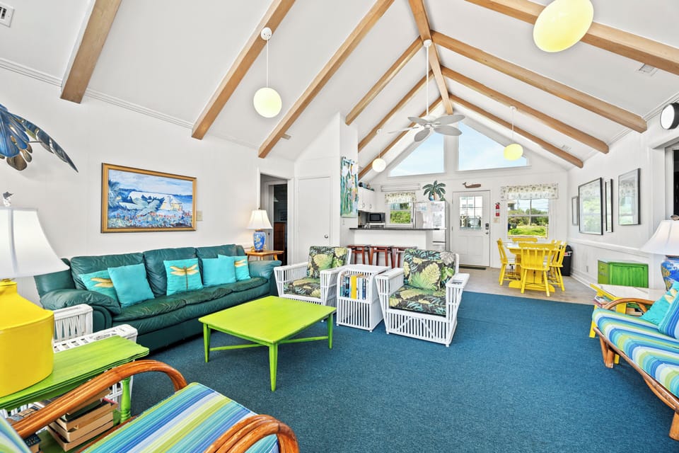 Step into your bright, open living space where vaulted ceilings with exposed beams create an airy, beachy vibe. Colorful furnishings, tropical accents, and plenty of room to relax set the stage for your coastal getaway.
